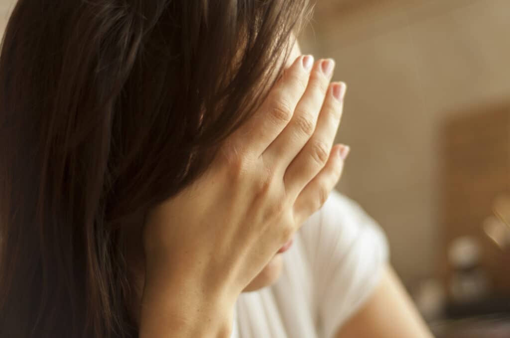 Brunette girl with headache holding hand on her head.