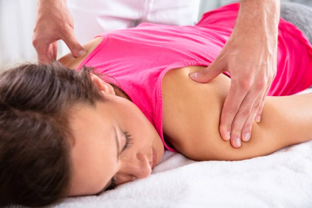 Close-up Of A Therapist's Hand Giving Shoulder Massage To Relaxed Female Patient