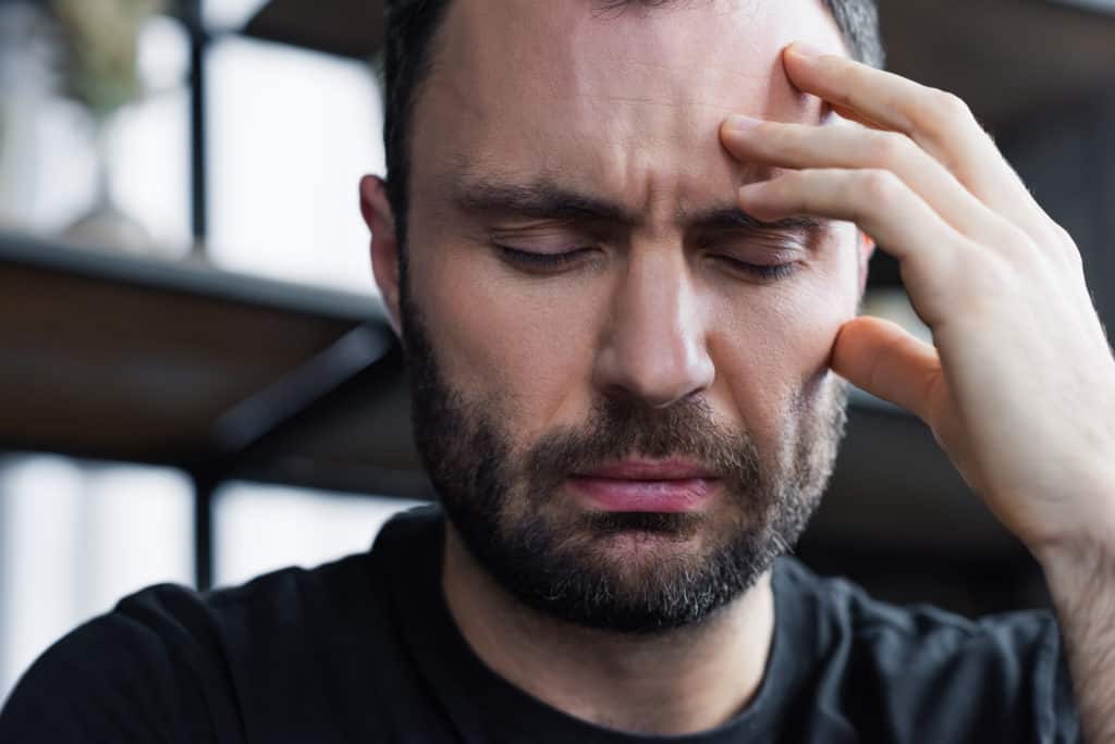 man with migraine holding head