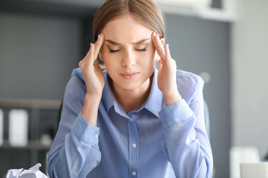 Young woman suffering from headache in office