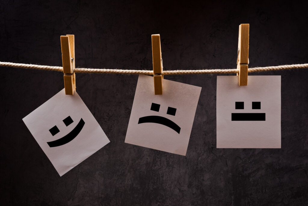 Emoticons printed on note paper attched to rope with clothes pins - happy, sad and neutral.