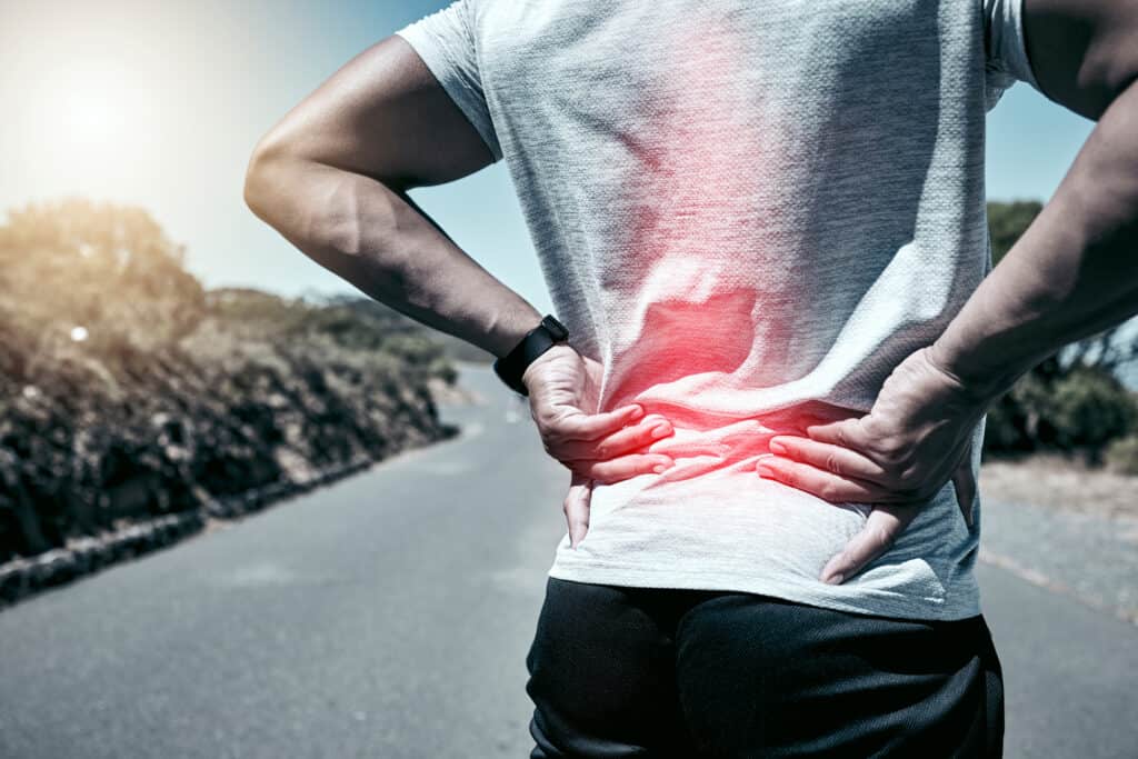 Fitness, back pain and injury with a sports man holding his sore body while outdoor for a workout. Exercise, anatomy and accident with a male athlete feeling tender while training or running alone.